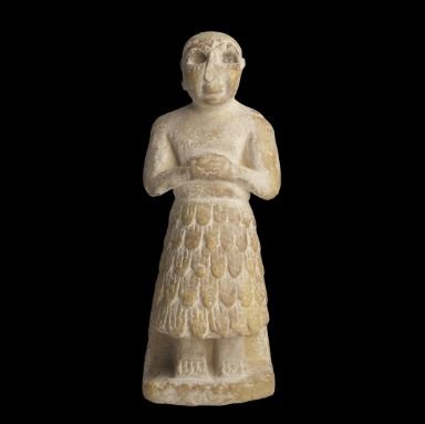 Estatua sumeria con ojos grandes en actitud devocional”